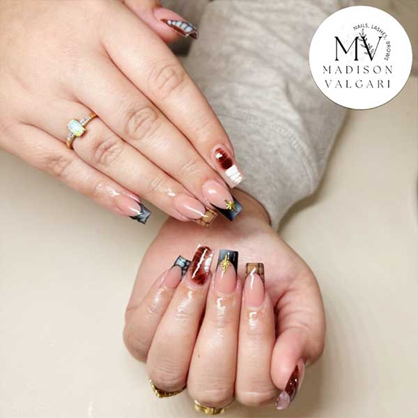 Square nails with tortoiseshell and deep red French tips and small gold star charms