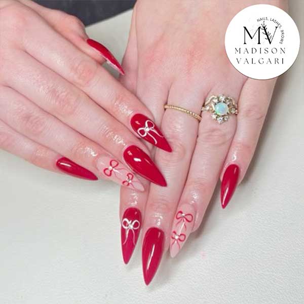 Glossy red stiletto nails with hand painted white bows