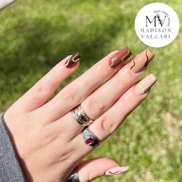 Nude and chocolate swirl nails photographed outdoors in daylight